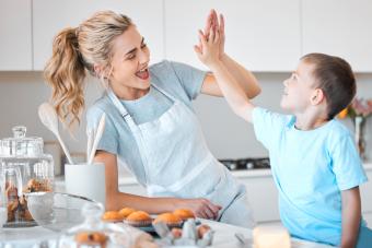 Cheerful mother giving her son a high five in the kitchen