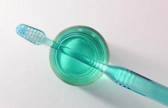 Toothbrush about to get disinfected in glass of mouthwash