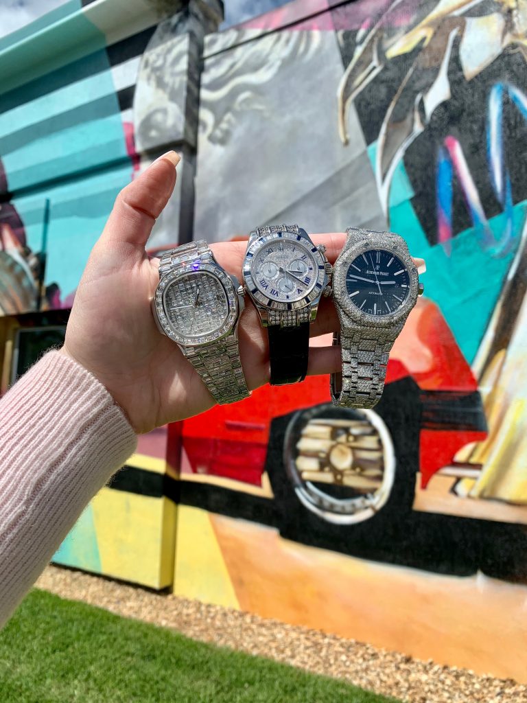 iced out watches held together, from left to right iced out Patek Philippe Nautilus, iced out Rolex and iced out AP Royal Oak watches